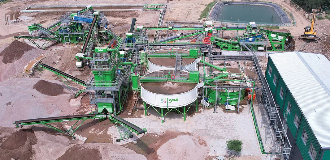 Aerial view of a green CFlo plant among pink-red ore stockpiles with settling ponds alongside