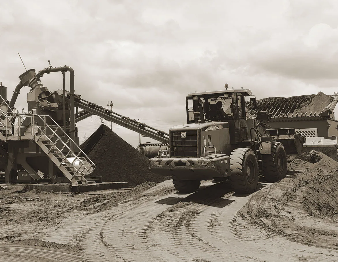 A wheel loader working beside a washing plant on a wet site between stockpiles