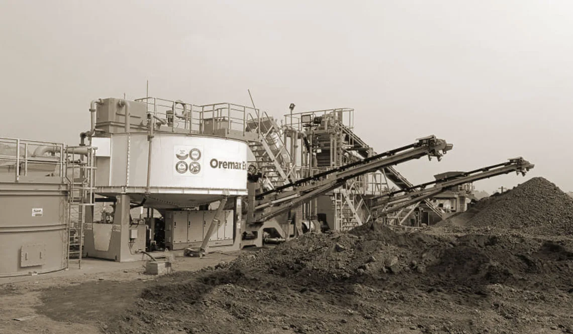 A CFlo Oremax unit working beside a dark heap of excavated ore