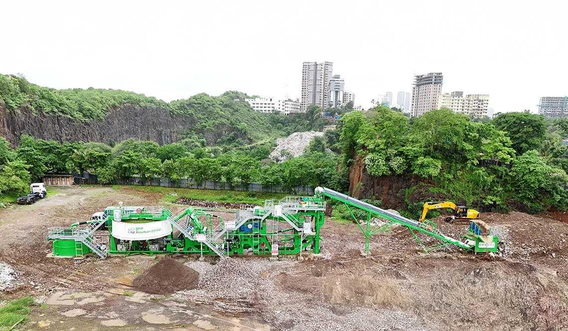 A green CFlo plant on a cleared site with a quarry face and city skyline behind