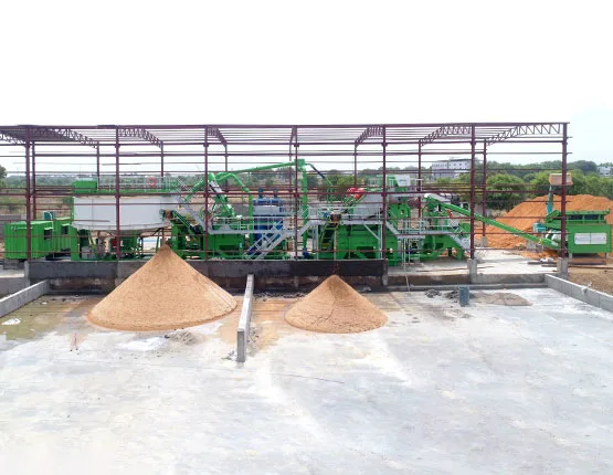 A green CFlo plant under a steel canopy, discharging two conical stockpiles of washed sand